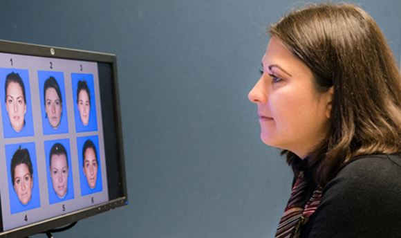 Queen Margaret University Psychology Student looking at a computer screen displaying 6 different faces numbered 1-6