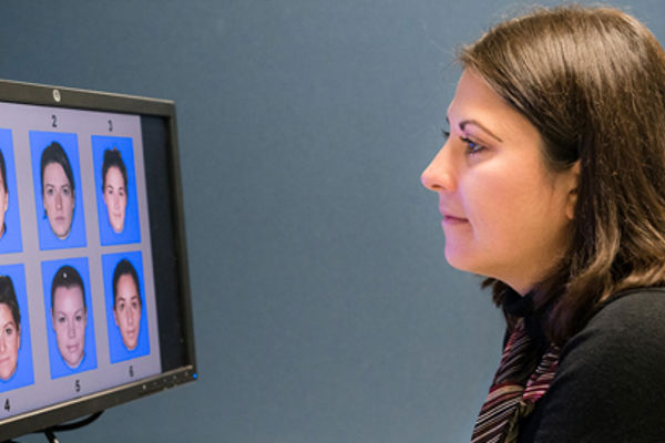 Queen Margaret University Psychology Student looking at a computer screen displaying 6 different faces numbered 1-6