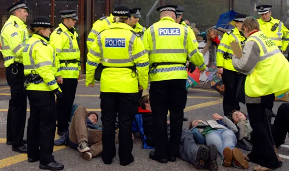 Police members surrounding a group of individuals lying on the street