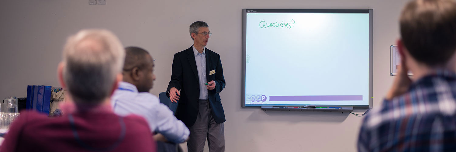 A man giving a presentation in front of an electronic whiteboard
