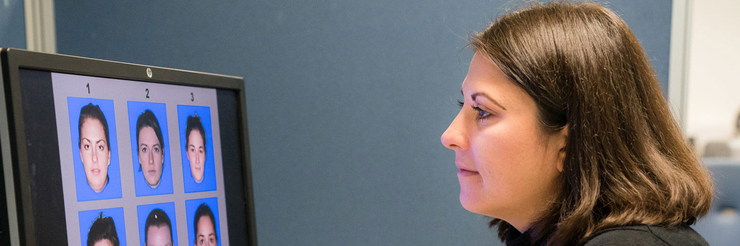 QMU Psychology Student looking at a computer screen displaying 6 different faces numbered 1-6