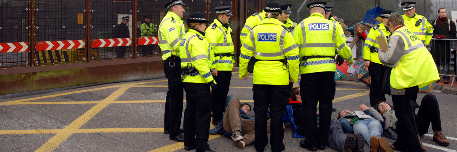 Police members surrounding a group of individuals lying on the street