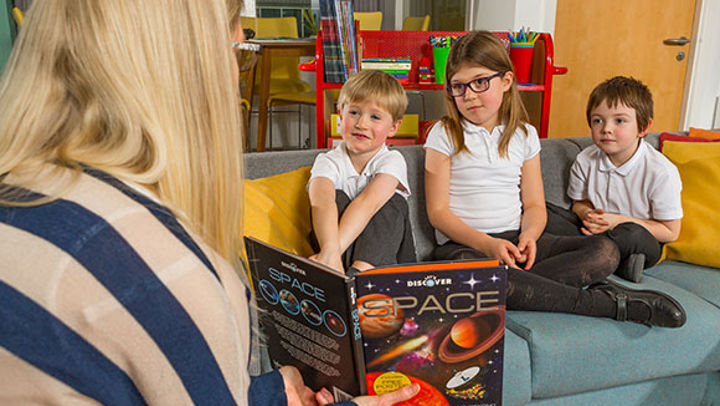 A teacher showing children a picture in a book
