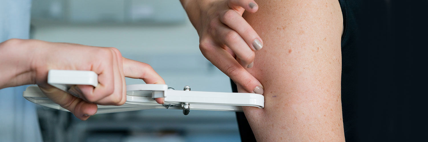 Close up of a dietician measuring the fat on an arm with a fat caliper