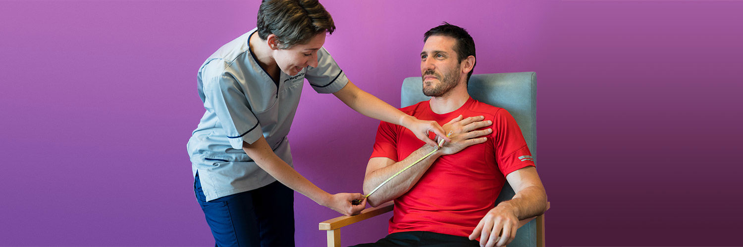 A Queen Margaret University student nurse examining the arm of a male patient