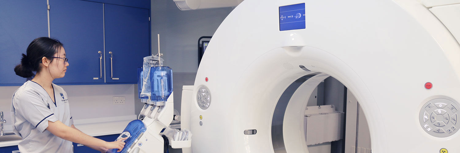 Student nurse standing beside a CT scanner