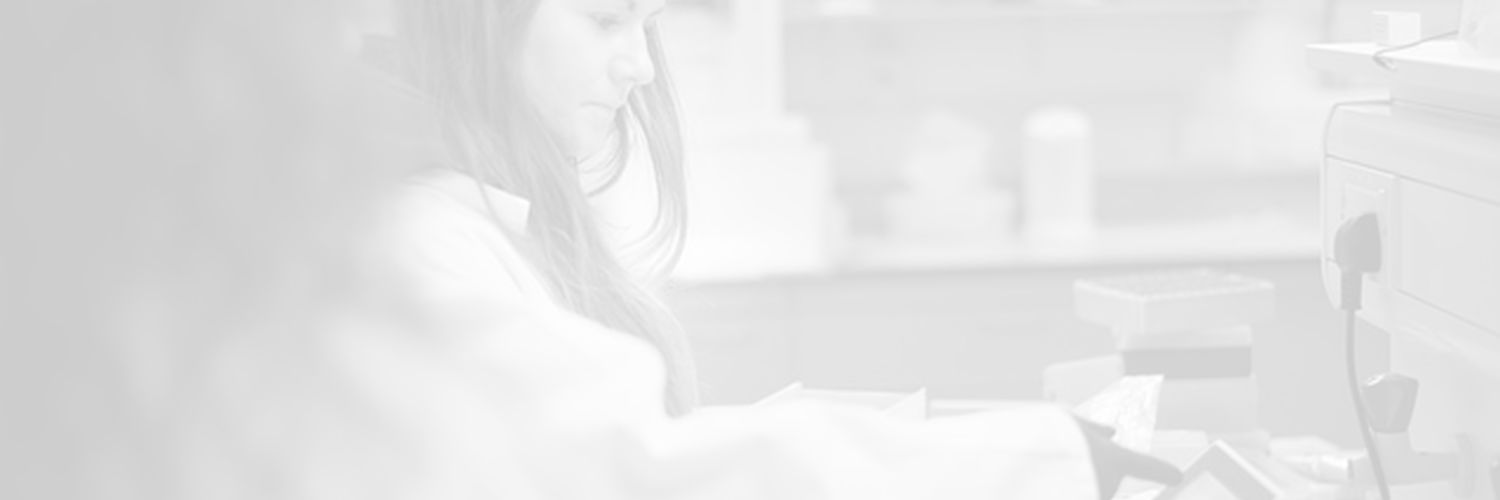 Faded image of two students in a laboratory wearing lab coats