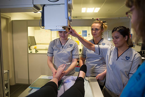 Radiography students directing an x-ray machine over a foot