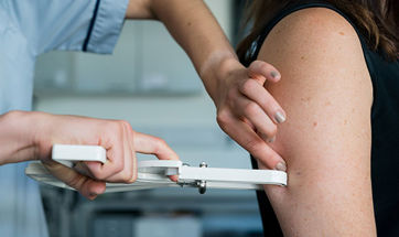 Close up of a dietician measuring the fat on an arm with a fat caliper 
