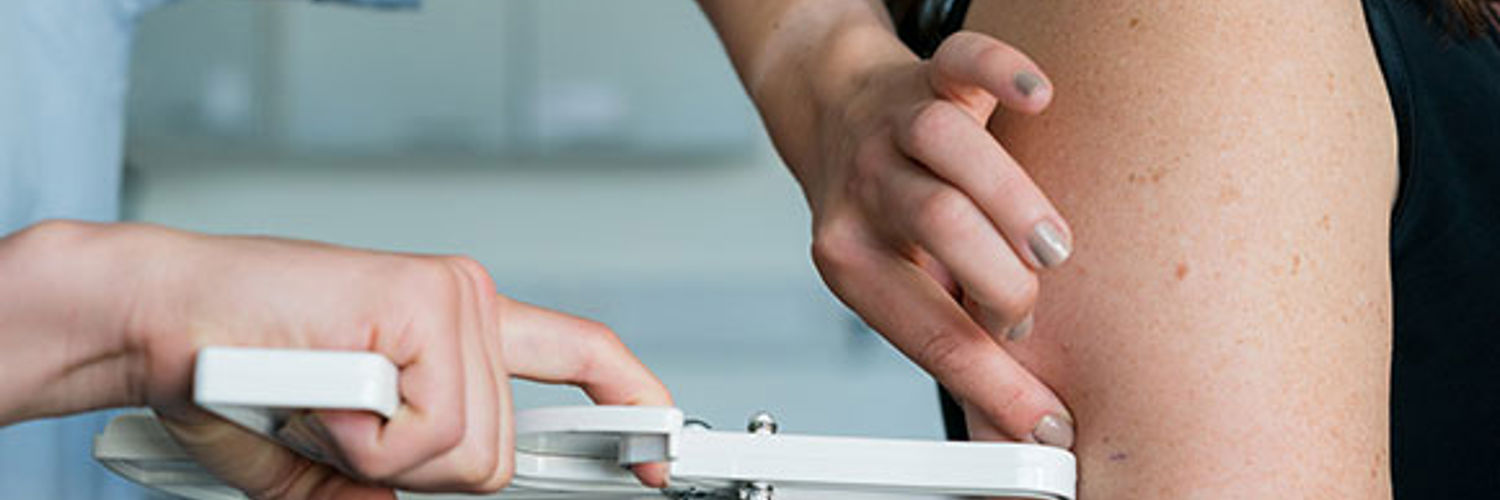 Close up of a dietician measuring the fat on an arm with a fat caliper 