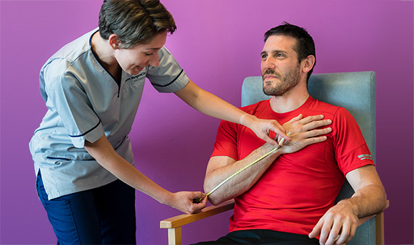 A Queen Margaret University student nurse examining the arm of a male patient