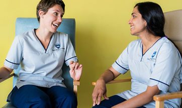 Two student nurses sitting together chatting and laughing