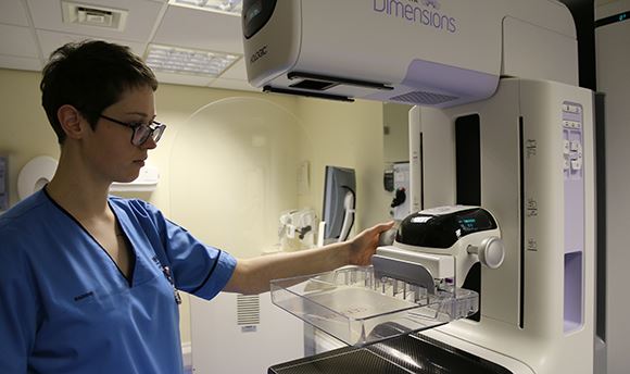 A student nurse standing by a mammography imaging machine