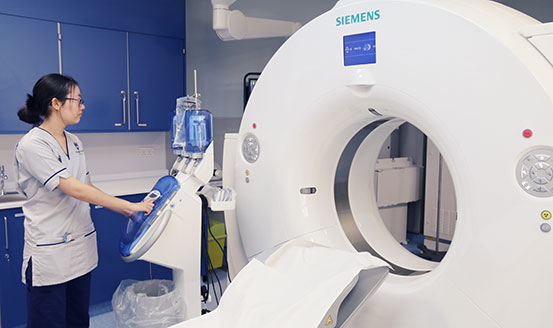 Student nurse standing beside a CT scanner