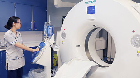 Student nurse standing beside a CT scanner