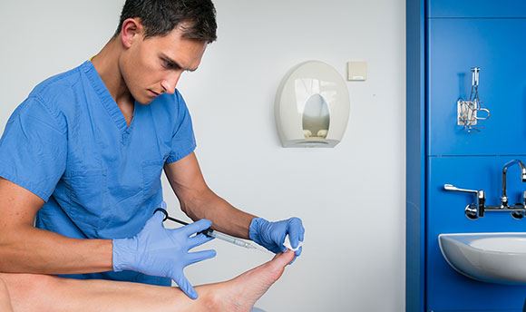 Student podiatrist injecting a toenail 