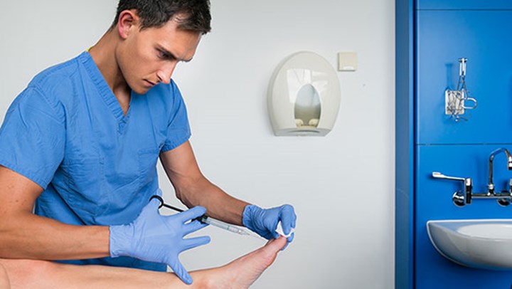 Student podiatrist injecting a toenail 