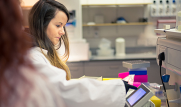 Two students in a laboratory wearing lab coats