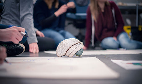 QMU students sitting on the floor looking at a model brain and doing a group project