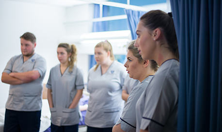 A row of QMU student nurses listening intently as a senior nurse speaks to them