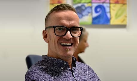 Smiling man with thick rimmed glasses looking directly at the camera