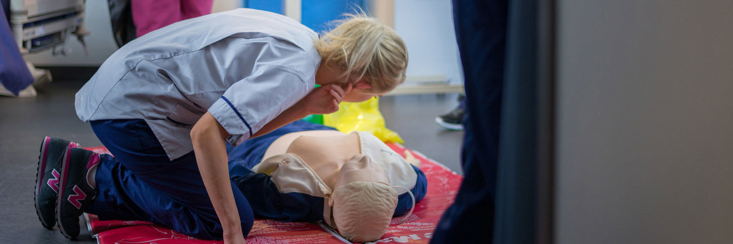 Queen Margaret University Nursing Student kneeling over a Resusci Annie doll