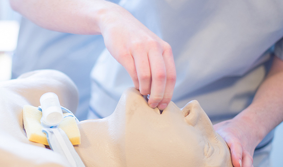 Student nurse practicing clearing the throat of a resuscitation doll