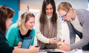Four students working on a group project poster together