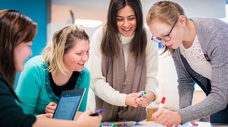 Four students working on a group project poster together