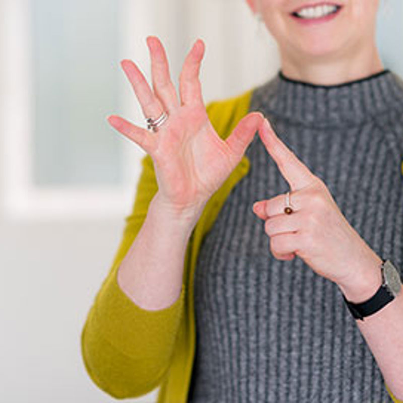 A woman in a yellow cardigan signing