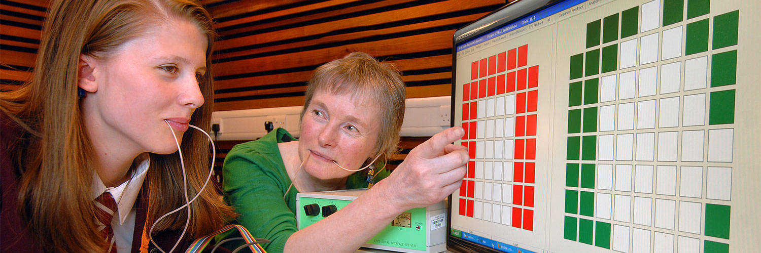 A student & Lecturer with probes in their mouths looking at a screen covered in coloured squares