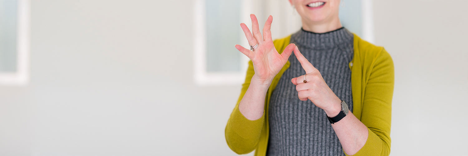A woman in a yellow cardigan signing