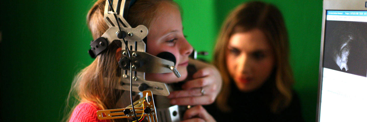 A child with a large piece of speech & language therapy equipment attached to their head