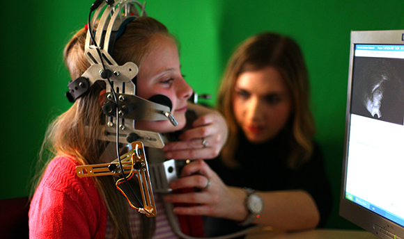 A child with a large piece of speech & language therapy equipment attached to their head