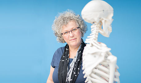 Dr Margaret Smith standing beside a skeleton
