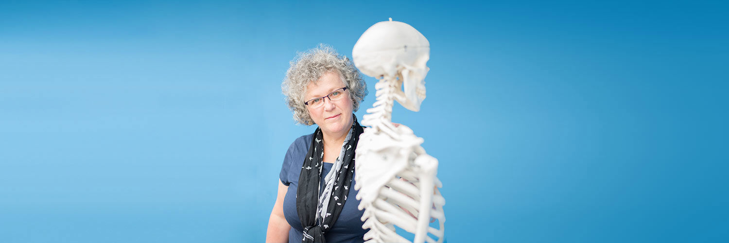 Dr Margaret Smith standing beside a skeleton