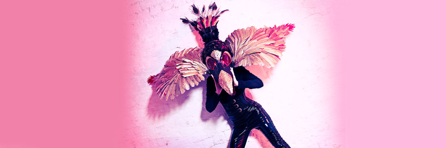 A QMU student posing in a vivid bird costume