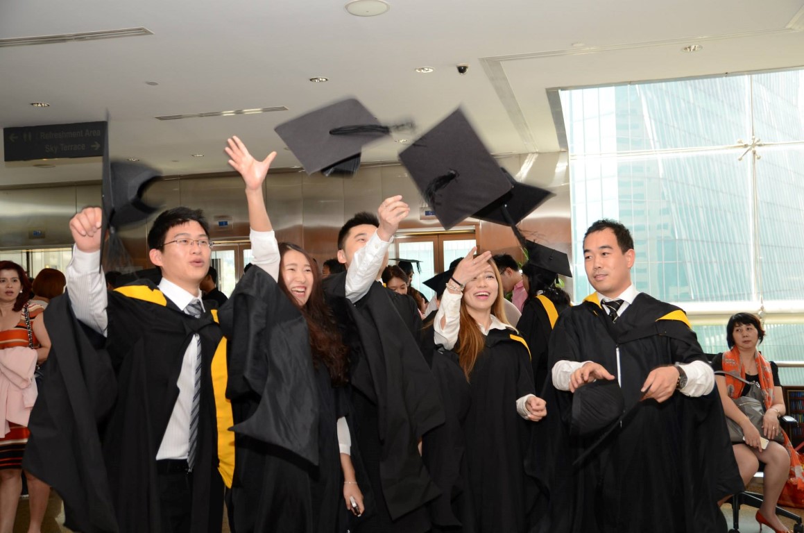 Group of students in their graduation gowns throwing their caps in the air