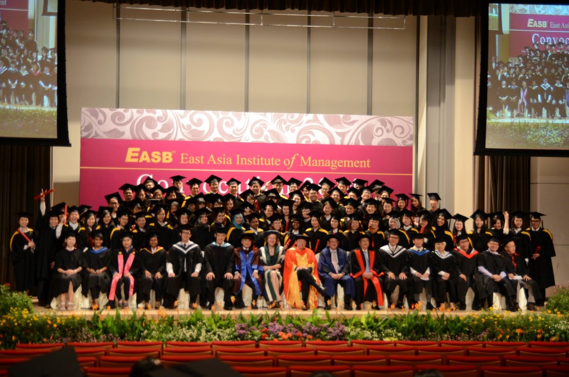 A stage full of graduating students in their caps and gown from the East Asia Institute of Management