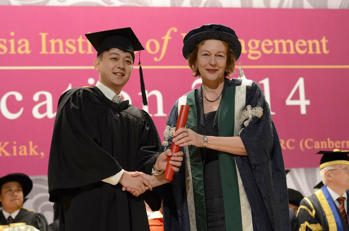 A graduate receiving their diploma on stage from QMU principal Petra Wend