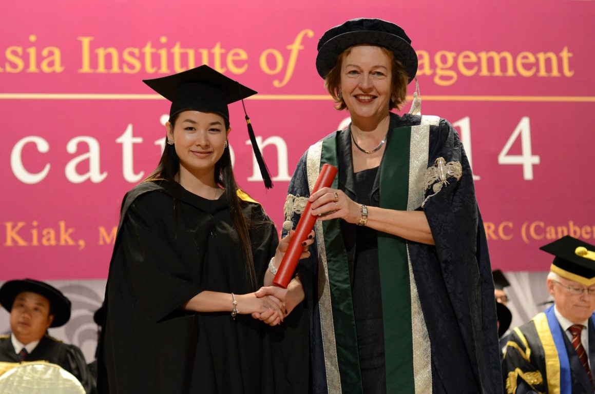 A graduate receiving their diploma on stage from QMU principal Petra Wend