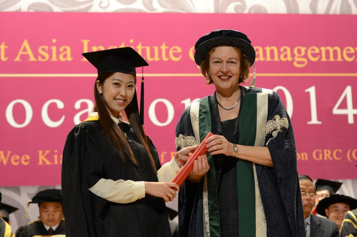 A graduate receiving their diploma on stage from QMU principal Petra Wend