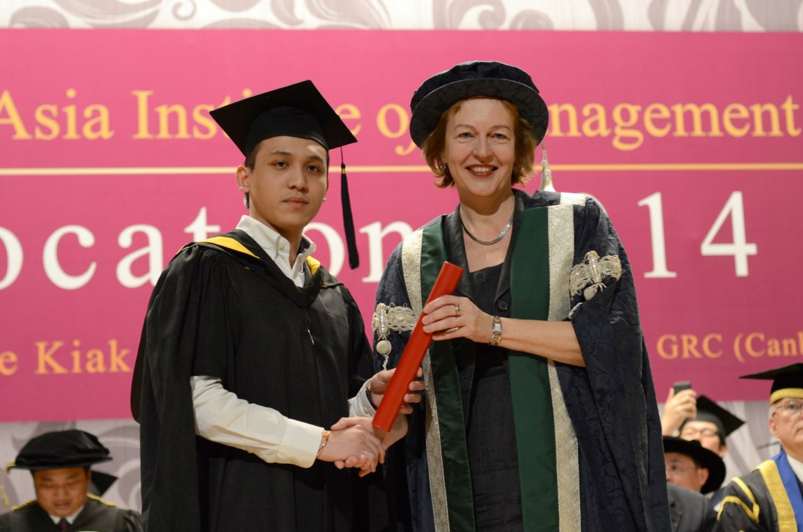 A graduate receiving their diploma on stage from QMU principal Petra Wend