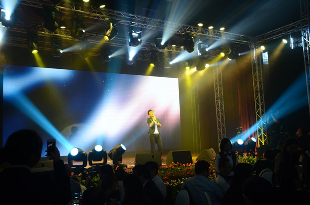 A performer on stage singing onto a mic with a professional light show happening