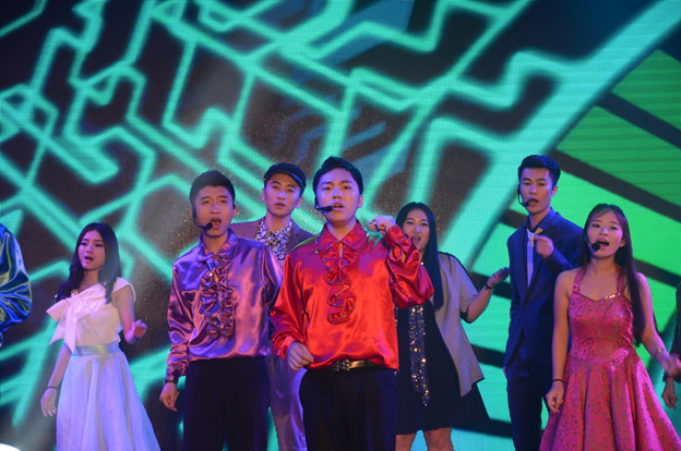 A stage filled with performers singing together
