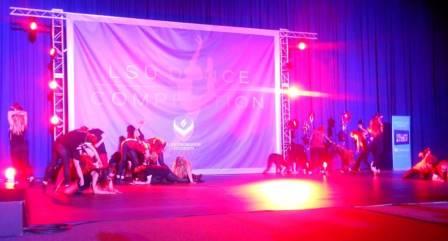 A group of performers doing interpretative dancing on a stage lit by red lights