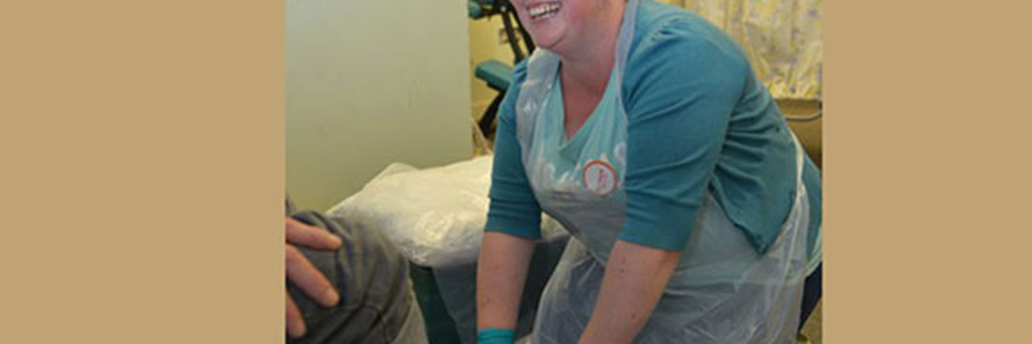 A QMU podiatry student washing a homeless person's feet