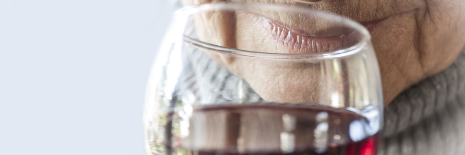 An elderly woman enjoying a glass of red wine