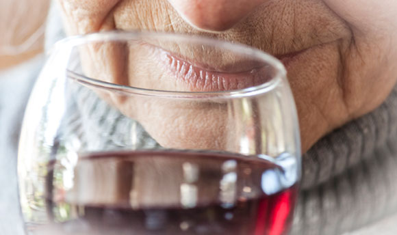 An elderly woman enjoying a glass of red wine