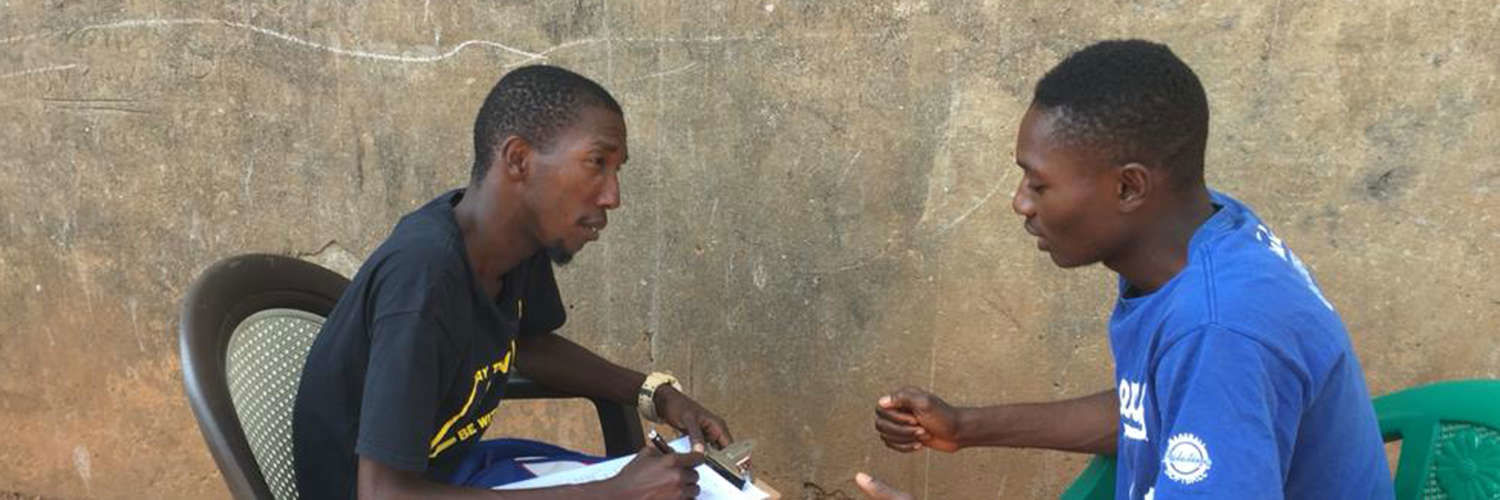 Sierra Leoneans filling in a form and having a discussion 